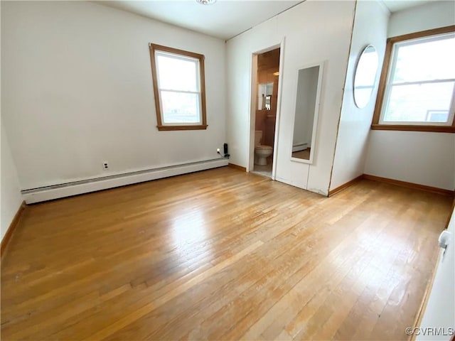 unfurnished bedroom featuring a baseboard heating unit, connected bathroom, and light wood-type flooring