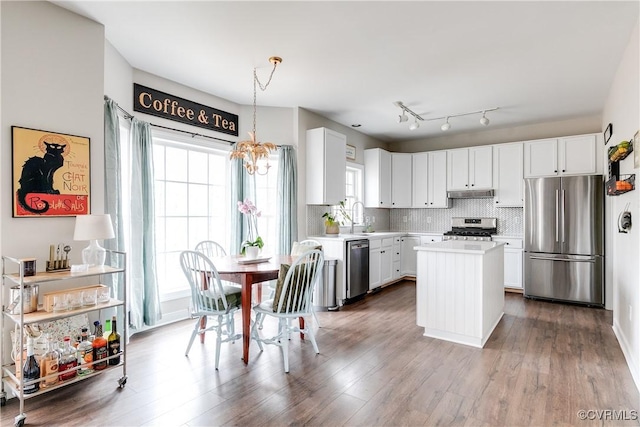 kitchen featuring stainless steel appliances, white cabinetry, hanging light fixtures, and a center island