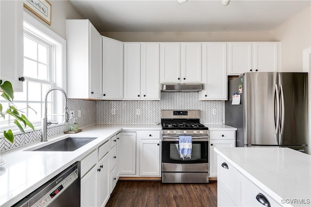 kitchen with sink, dark wood-type flooring, appliances with stainless steel finishes, white cabinets, and decorative backsplash