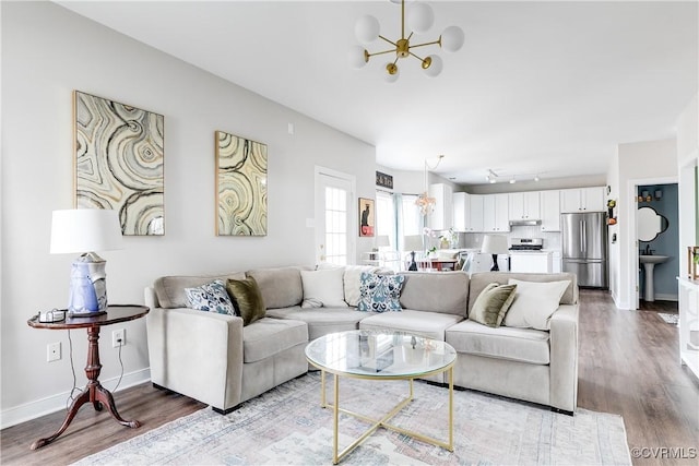 living room featuring sink, a notable chandelier, light hardwood / wood-style floors, and track lighting