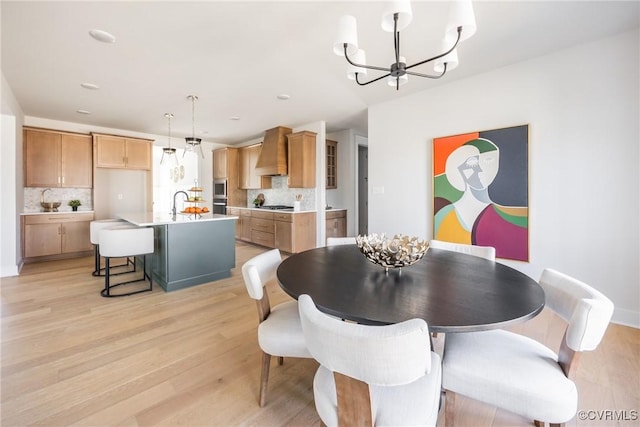 dining room with light hardwood / wood-style flooring, sink, and a chandelier