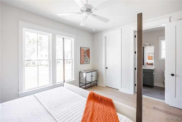 bedroom with ceiling fan, light hardwood / wood-style flooring, sink, and connected bathroom