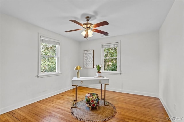 home office with light wood-style floors, baseboards, and a ceiling fan