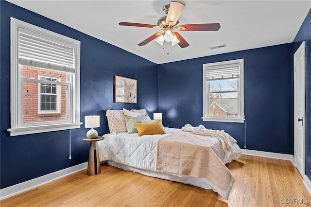 bedroom featuring a ceiling fan, visible vents, baseboards, and wood finished floors