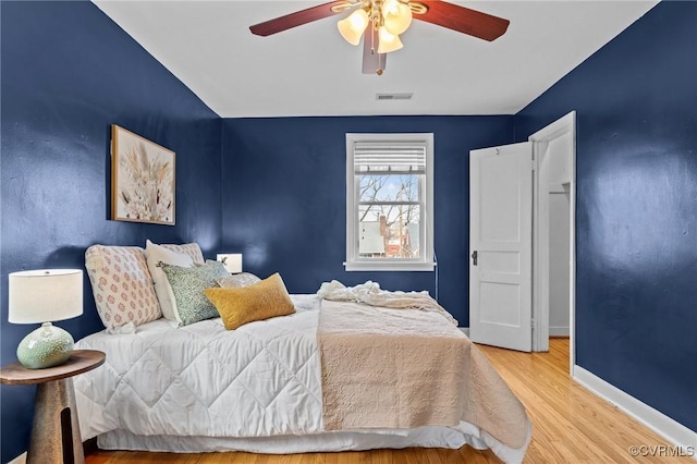 bedroom with baseboards, visible vents, ceiling fan, and wood finished floors