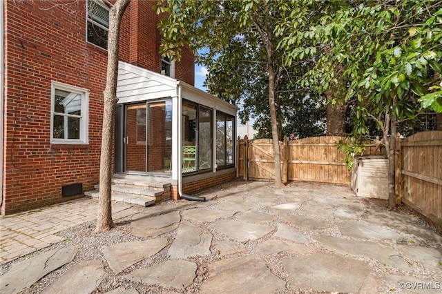 view of patio / terrace featuring a sunroom, fence, and a gate