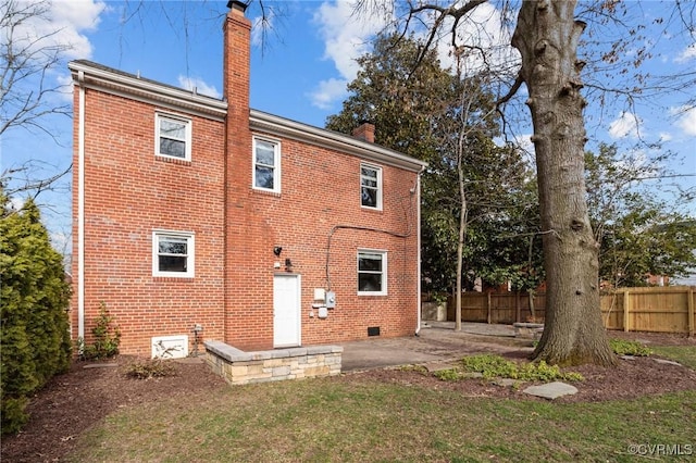 back of property featuring a chimney, fence, a yard, a patio area, and brick siding