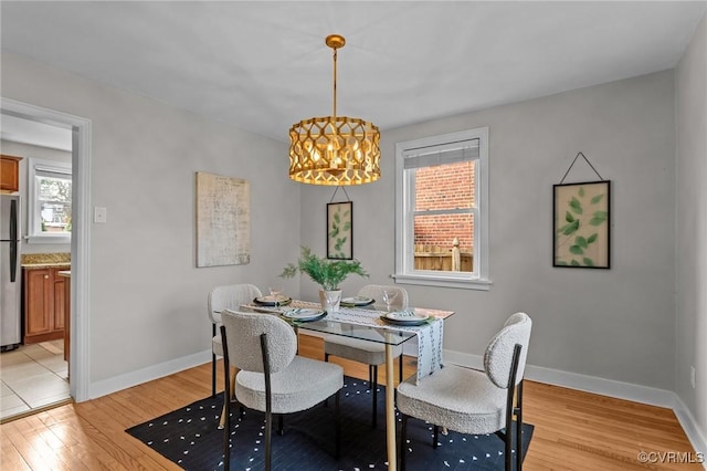 dining area featuring baseboards, an inviting chandelier, and light wood-style floors