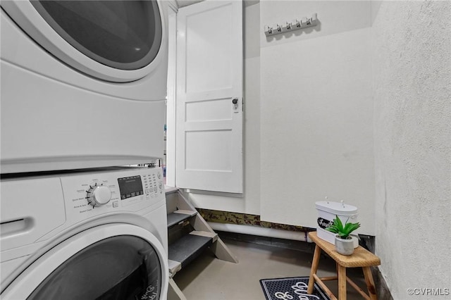 laundry room with stacked washer / dryer, laundry area, and a textured wall