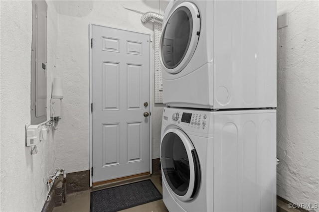 washroom with laundry area, a textured wall, and stacked washer and clothes dryer