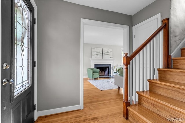 entryway with baseboards, a healthy amount of sunlight, stairway, and light wood finished floors