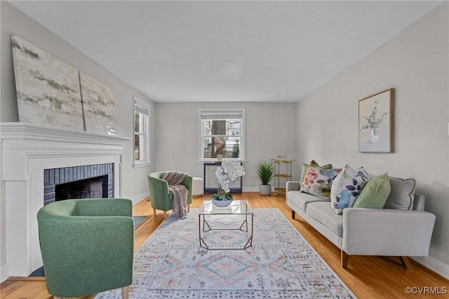 living area featuring a fireplace, wood finished floors, and baseboards