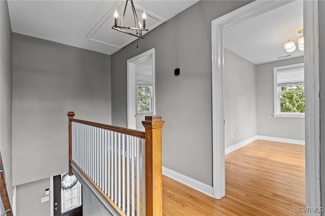 hallway with attic access, baseboards, wood finished floors, and an upstairs landing