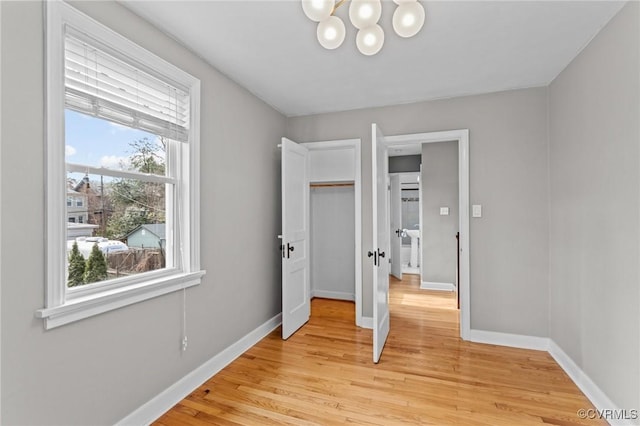 bedroom featuring light wood-style floors, a notable chandelier, and baseboards