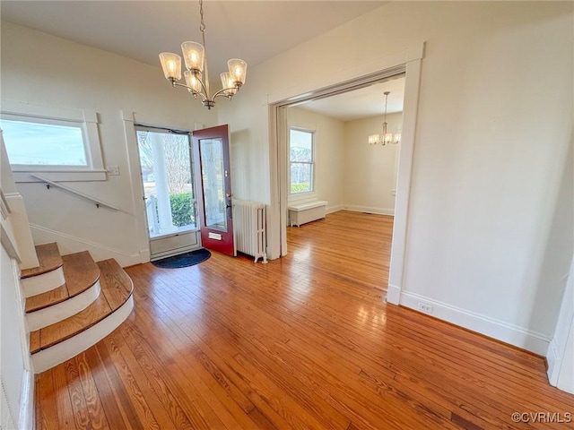 foyer entrance featuring light hardwood / wood-style floors, radiator, and a notable chandelier