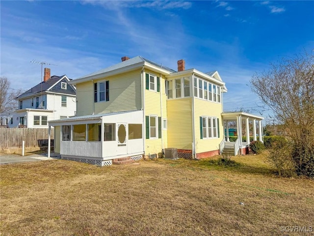 back of property featuring a lawn, a sunroom, and cooling unit