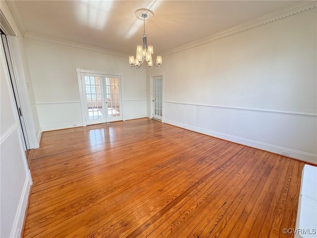 spare room featuring ornamental molding, wood-type flooring, an inviting chandelier, and french doors