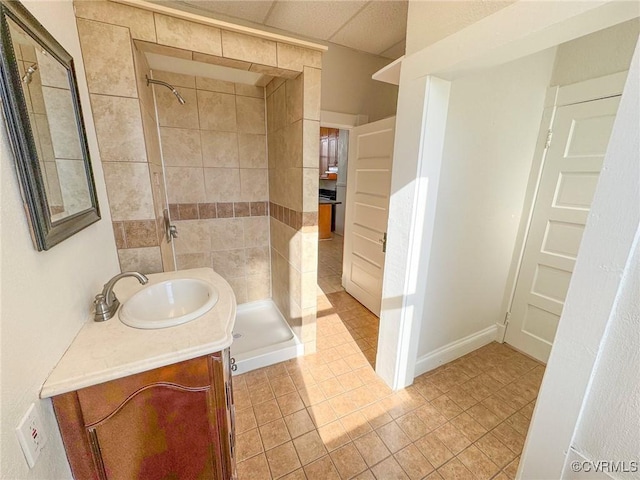 bathroom with a tile shower, vanity, and tile patterned flooring