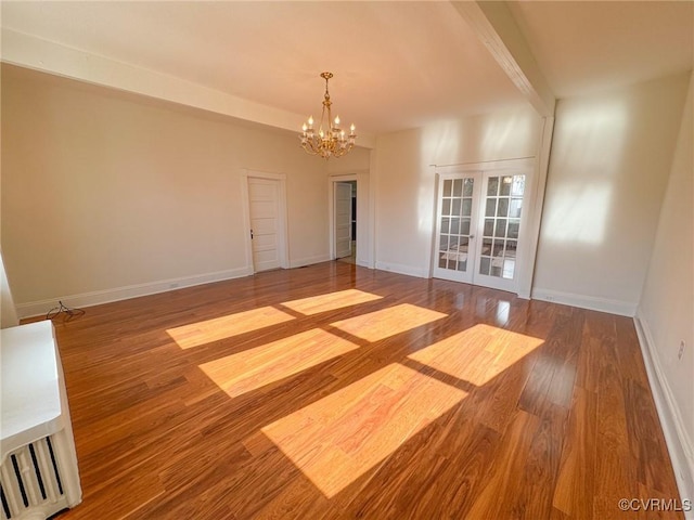 spare room with hardwood / wood-style flooring, an inviting chandelier, and french doors