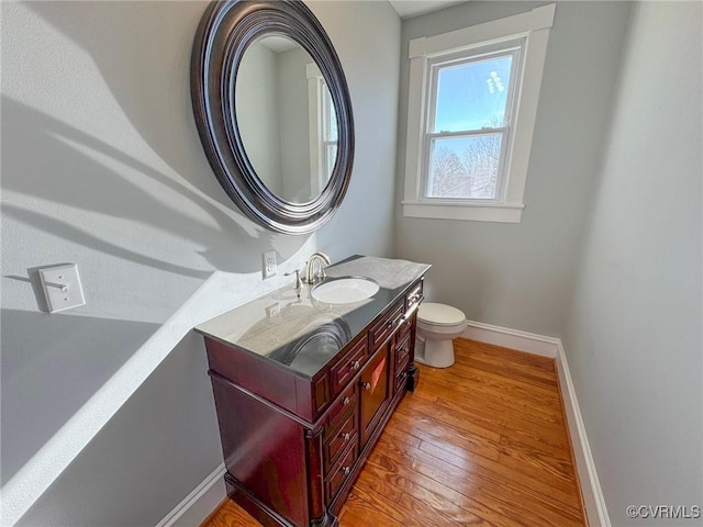 bathroom with toilet, vanity, and wood-type flooring