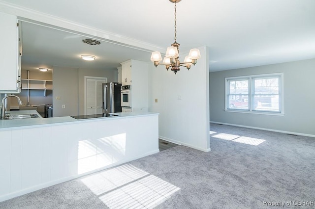 kitchen featuring sink, decorative light fixtures, stainless steel fridge, white cabinets, and white oven