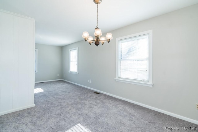 spare room with a chandelier and light colored carpet