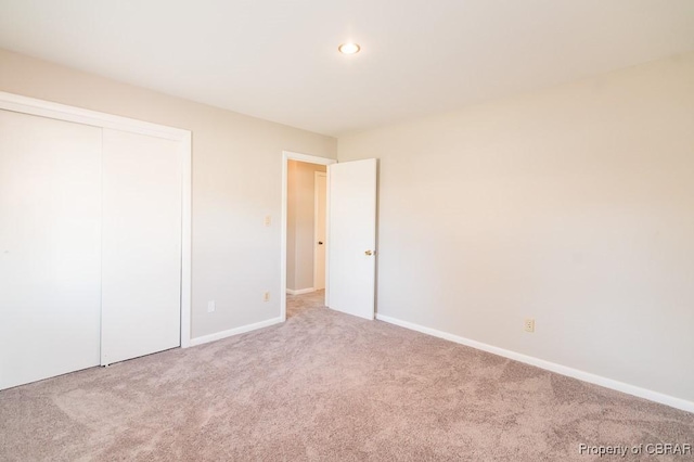 unfurnished bedroom featuring a closet and light colored carpet