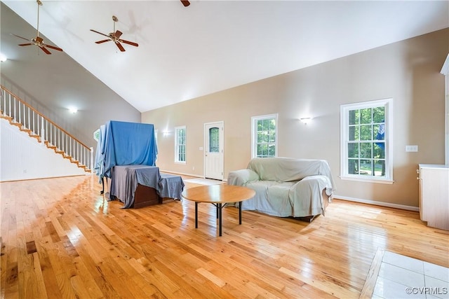 living room with light wood-style flooring, baseboards, and high vaulted ceiling