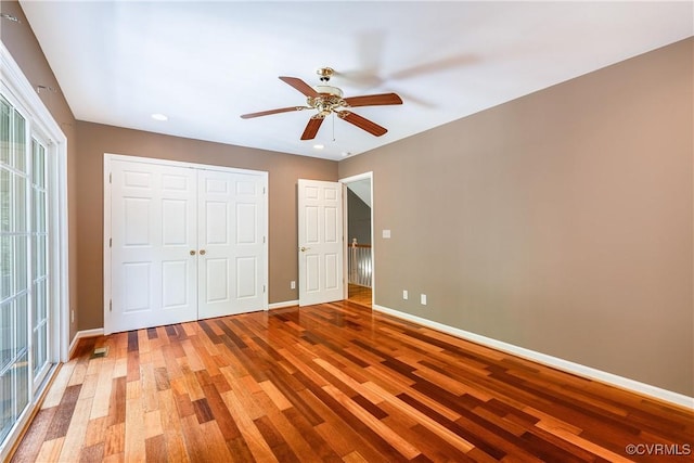 unfurnished bedroom with a ceiling fan, baseboards, a closet, and wood finished floors