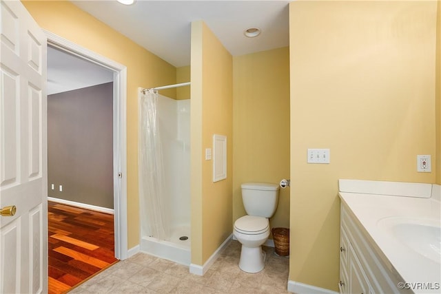 bathroom featuring baseboards, vanity, toilet, and a stall shower