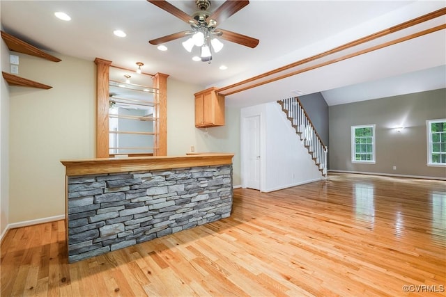 bar featuring ceiling fan, baseboards, light wood-style floors, and stairway