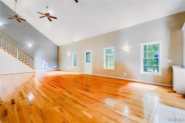 unfurnished living room featuring light wood finished floors, high vaulted ceiling, and baseboards