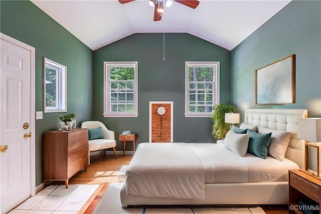 bedroom featuring vaulted ceiling, light wood-style flooring, a ceiling fan, and multiple windows