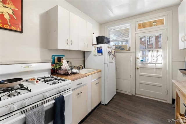 kitchen with dark wood-style floors, light countertops, a sink, white appliances, and white cabinetry