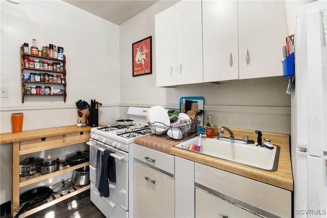 kitchen featuring a sink, white gas range oven, light countertops, and white cabinetry