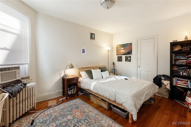 bedroom with baseboards, cooling unit, wood finished floors, and radiator