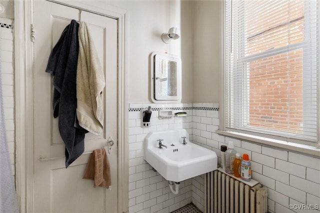 bathroom with radiator, a wainscoted wall, a sink, and tile walls