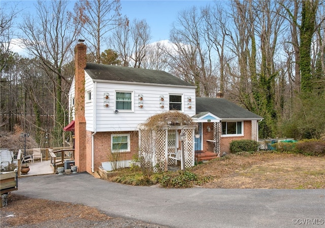 view of front of house featuring driveway, a chimney, and brick siding