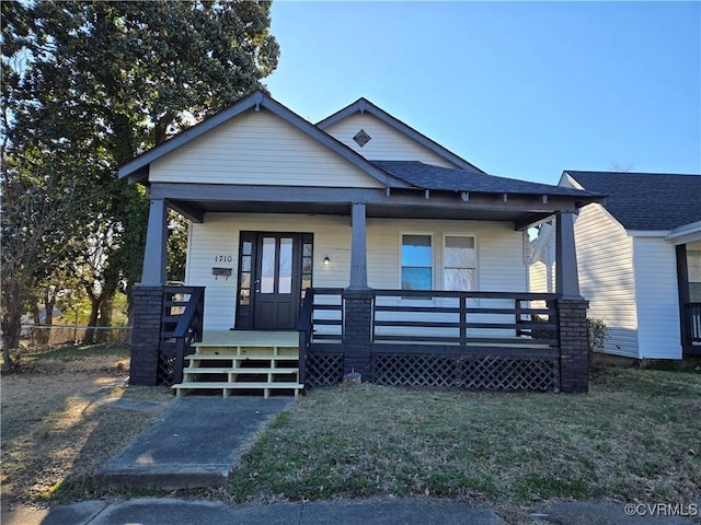 bungalow with a porch and a front lawn