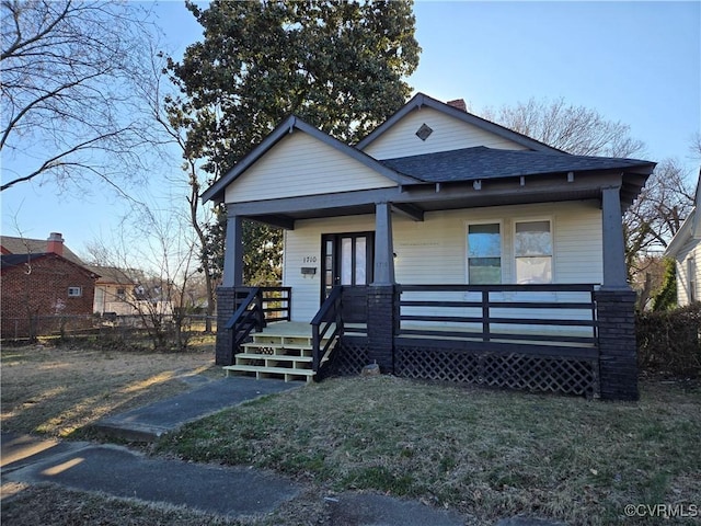 view of front facade featuring a front yard, a porch, and roof with shingles