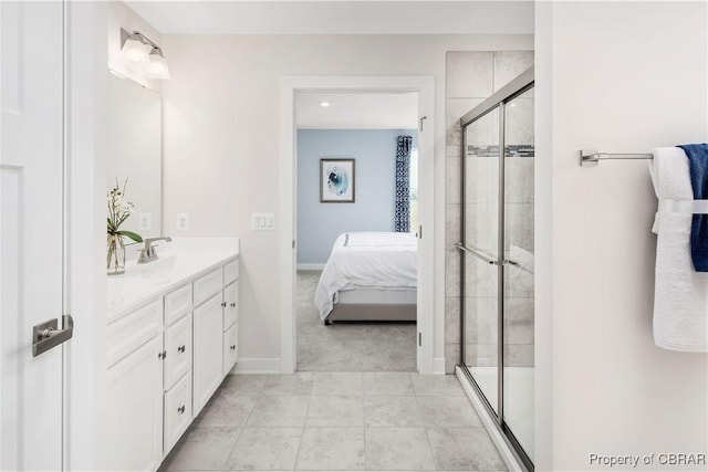 ensuite bathroom with connected bathroom, a sink, baseboards, double vanity, and a stall shower