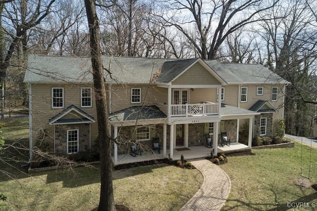 rear view of property with a balcony, a lawn, stone siding, and a patio