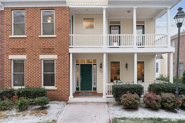 exterior space with a balcony, a porch, and brick siding