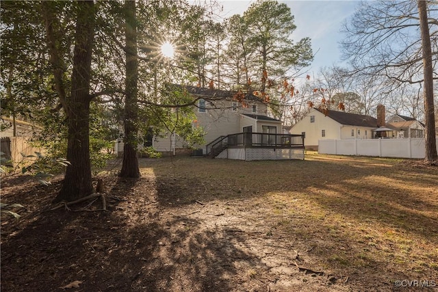 back of property with a lawn, a wooden deck, and fence