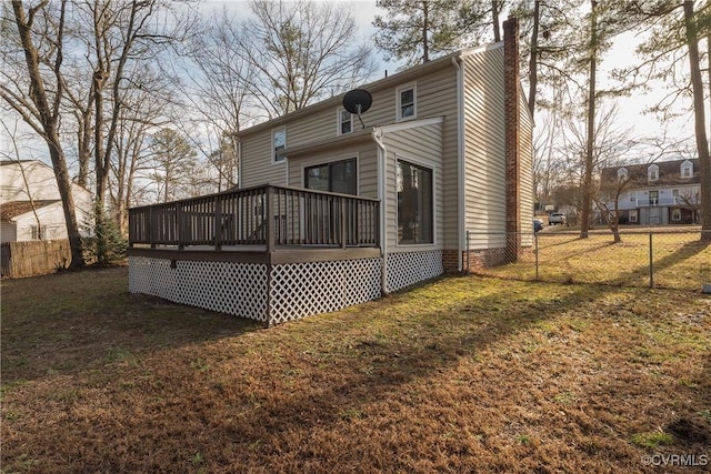 rear view of house featuring a lawn, a chimney, fence, and a wooden deck