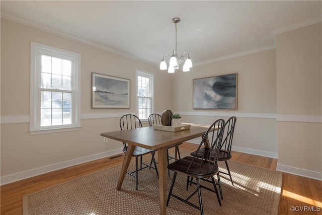 dining area with ornamental molding, a notable chandelier, baseboards, and wood finished floors