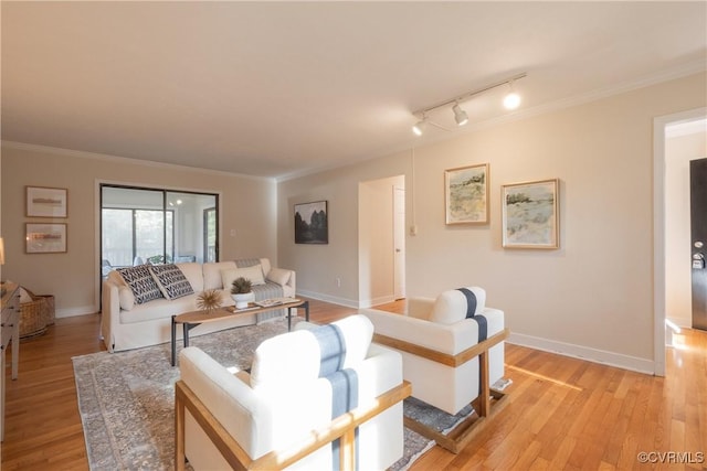 living room with ornamental molding, track lighting, light wood-style flooring, and baseboards