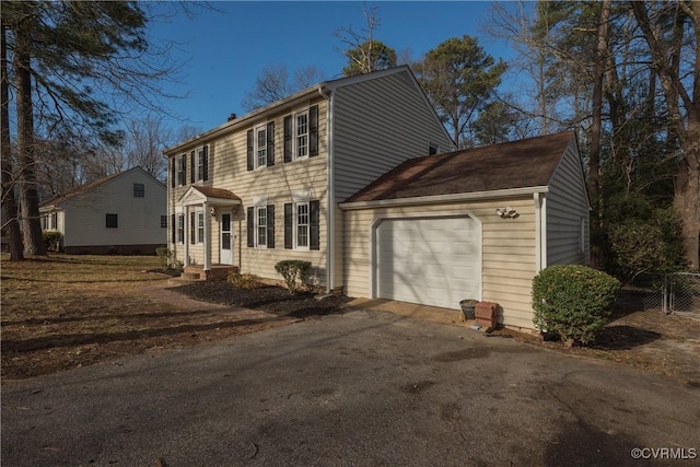 colonial-style house with driveway, an attached garage, and fence