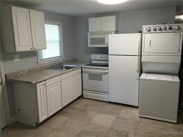 kitchen featuring stacked washer / drying machine, light countertops, white cabinetry, a sink, and white appliances