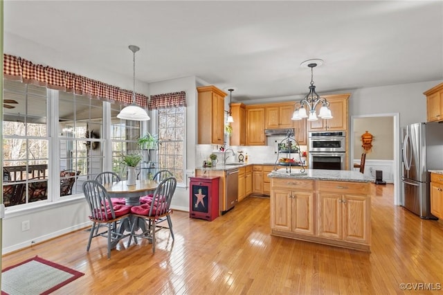 kitchen featuring a center island, pendant lighting, a notable chandelier, appliances with stainless steel finishes, and light wood-type flooring